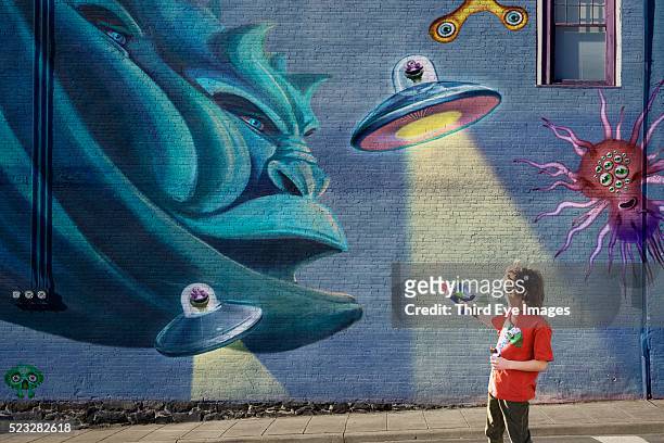 boy shooting aliens painted on a wall - bizarre scene stock pictures, royalty-free photos & images