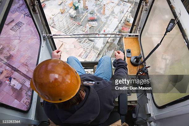 worker operating crane at construction site - construction cranes stockfoto's en -beelden