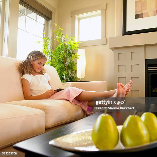 girl reading book in living room - teen girl barefoot at home stock pictures, royalty-free photos & images