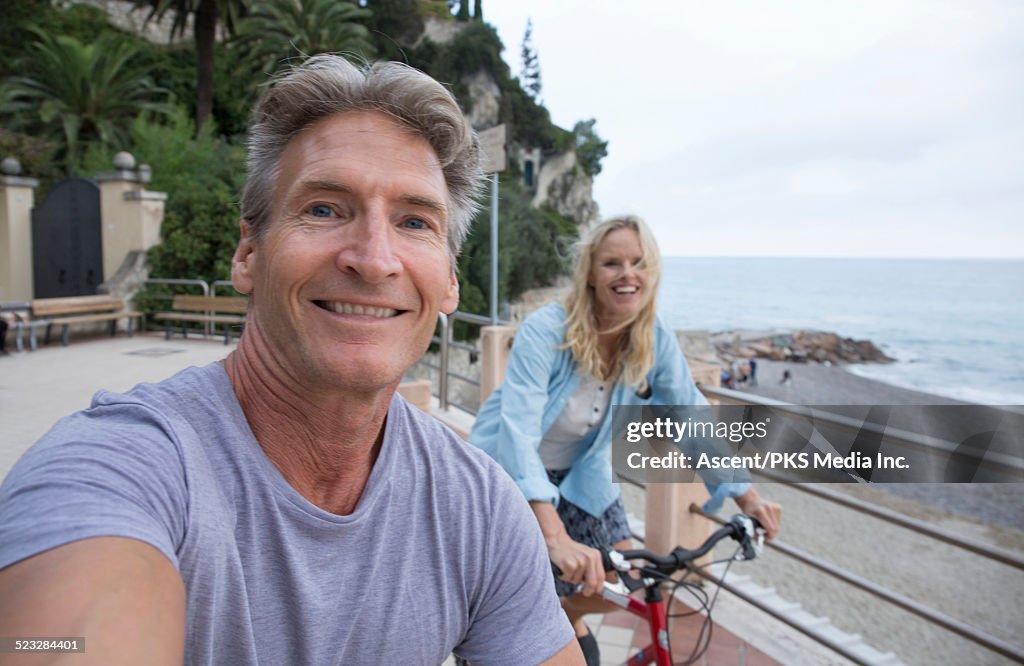 Couple take selfie portrait while riding bikes,sea