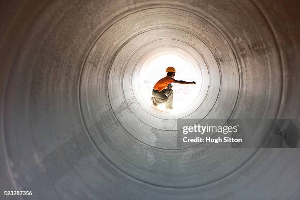 construction worker inspecting pipeline in desert - oil pipeline stock pictures, royalty-free photos & images