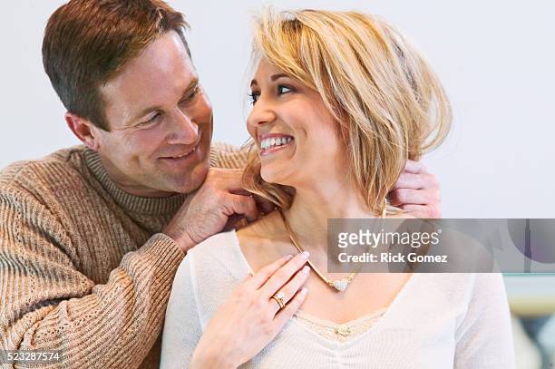 woman receiving necklace from man - couple jewelry stockfoto's en -beelden