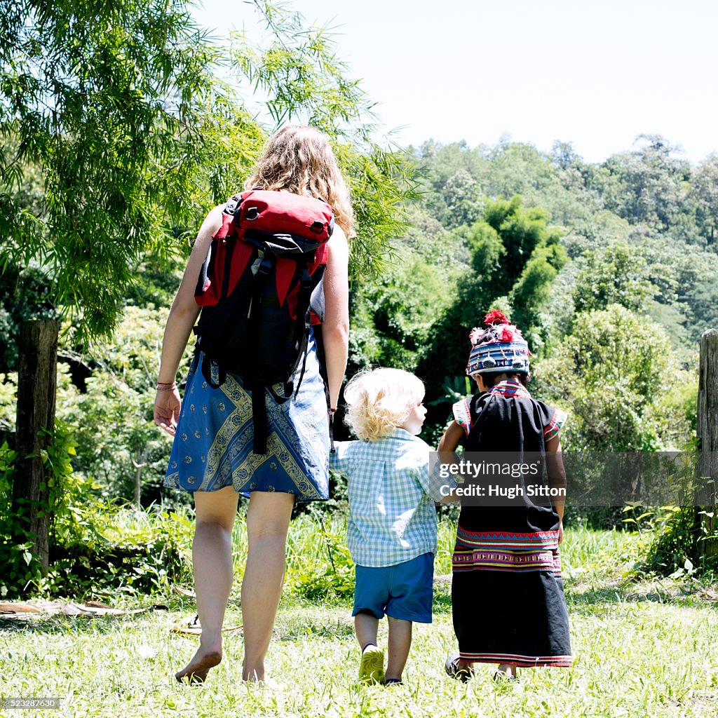 Young woman walking with her son (12-23 months) and local child (4-5), Chiang Mai, Thailand