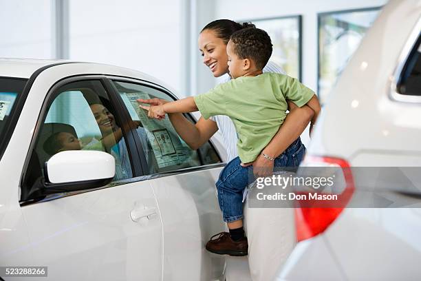 woman and son looking at car's sticker price - car shopping stock-fotos und bilder