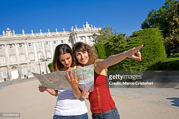 tourists looking at map in front of royal palace - koninklijk paleis van madrid stockfoto's en -beelden