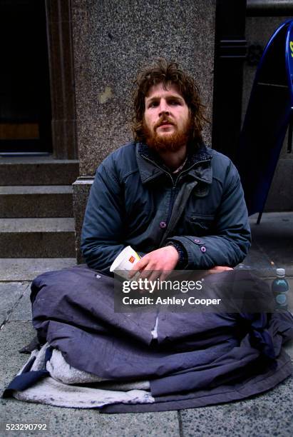 homeless person sitting on pavement - homeless person fotografías e imágenes de stock