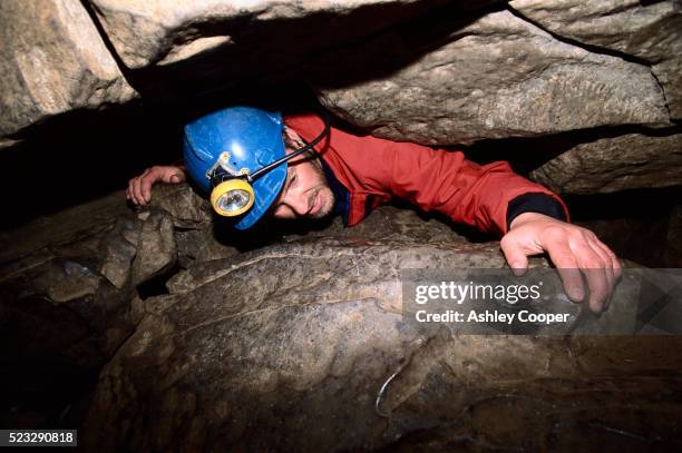 spelunker crawling along narrow space - pothole stock-fotos und bilder