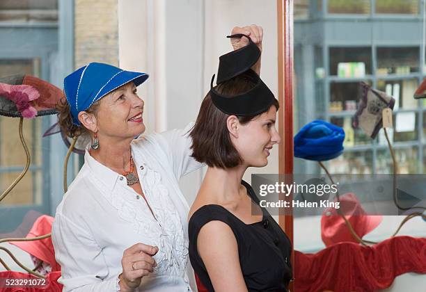 woman trying on a hat - hat maker stock pictures, royalty-free photos & images