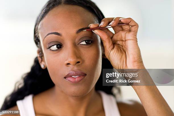woman tweezing eyebrows - tweezing eyebrows stock pictures, royalty-free photos & images