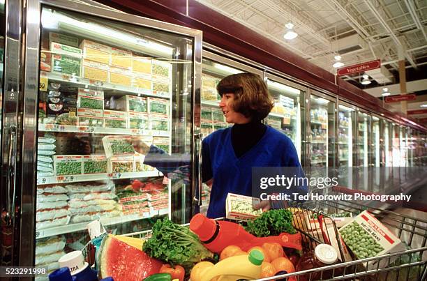 woman filling shopping cart at supermarket - frozen food bildbanksfoton och bilder