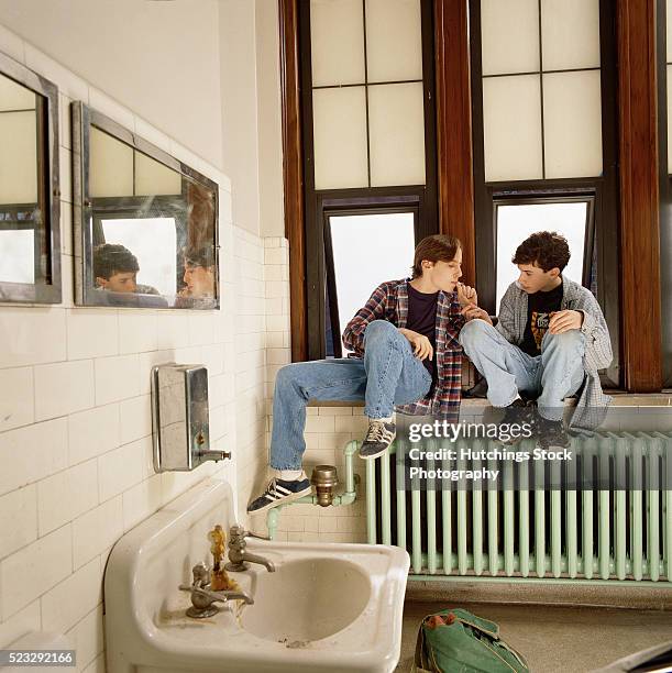 kids sharing a marijuana cigarette in a school bathroom - human joint stockfoto's en -beelden