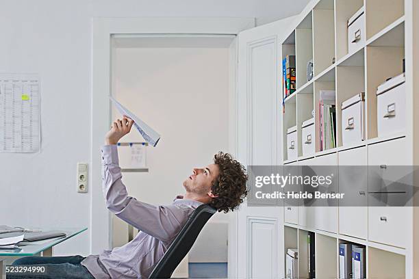 businessman holding paper airplane - boring man stock-fotos und bilder