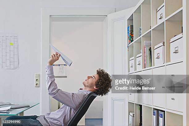 businessman holding paper airplane - bores stock pictures, royalty-free photos & images