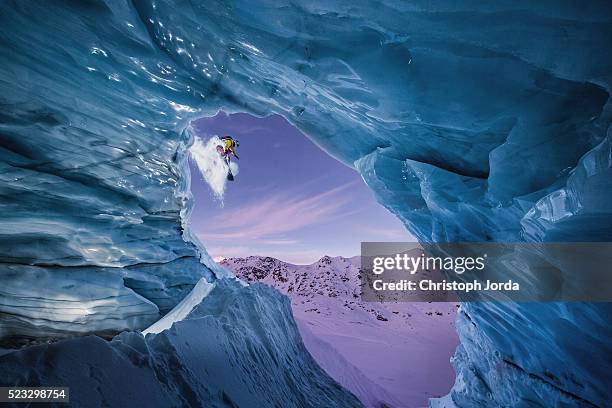 snowboarder jumping down from a glacier cave - freestyle snowboarding fotografías e imágenes de stock