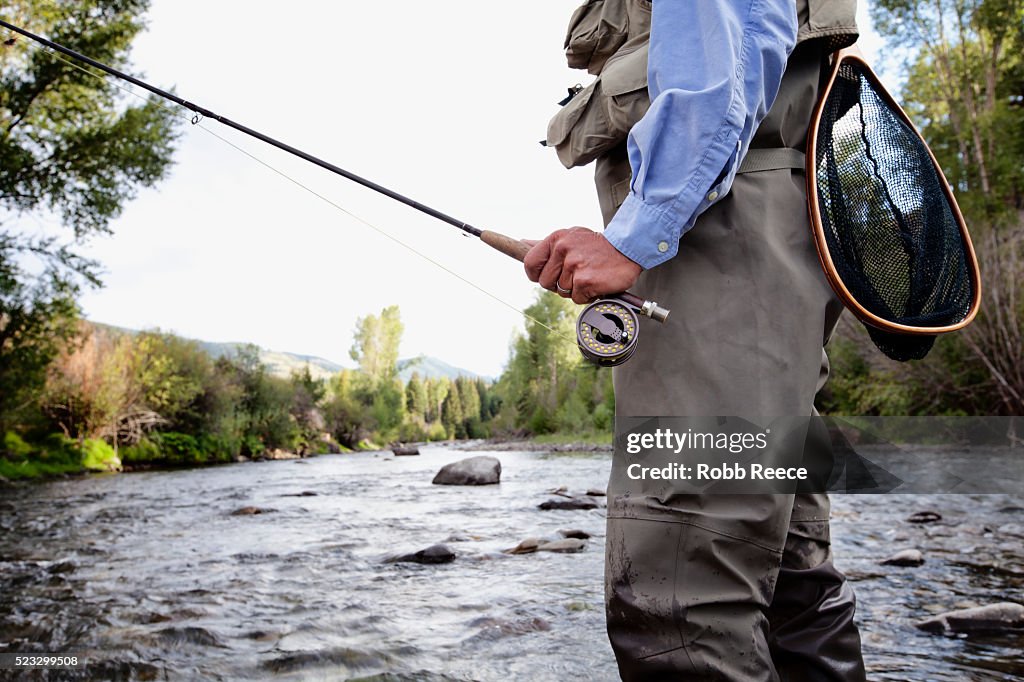 A male fly fisherman walks in a Colorado stream near Lake City, Colorado