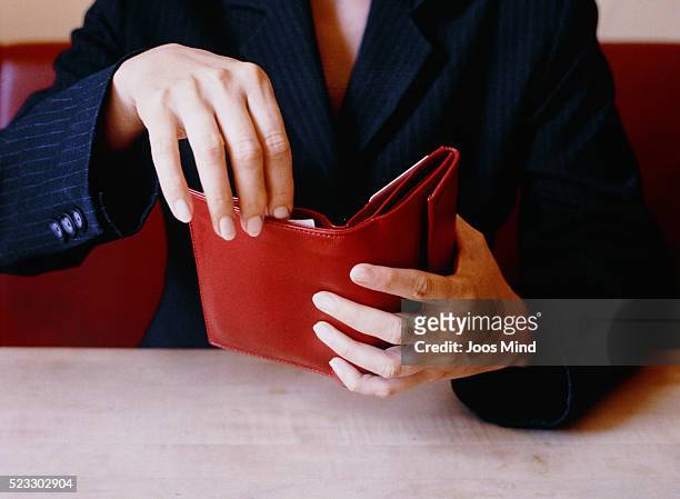 businesswoman opening red wallet at table - wallet stock-fotos und bilder