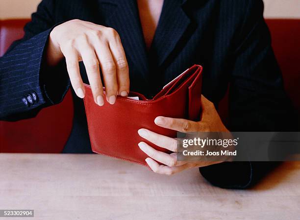 businesswoman opening red wallet at table - cartera fotografías e imágenes de stock