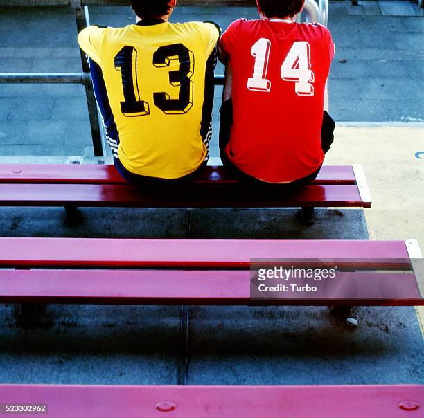 two young men in soccer jerseys on bench - trikot stock-fotos und bilder