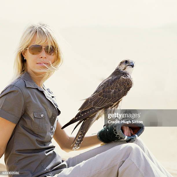 woman holding falcon - cetrería fotografías e imágenes de stock