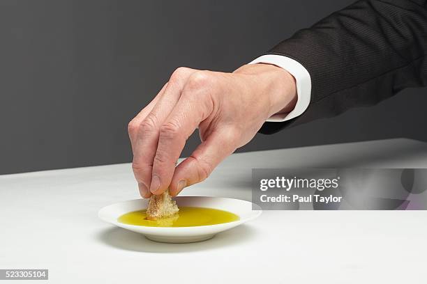 man dipping bread into small dish of olive oil - dipping fotografías e imágenes de stock