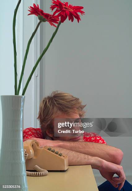 young man sitting at phone and flowers in vase - impatience flowers - fotografias e filmes do acervo