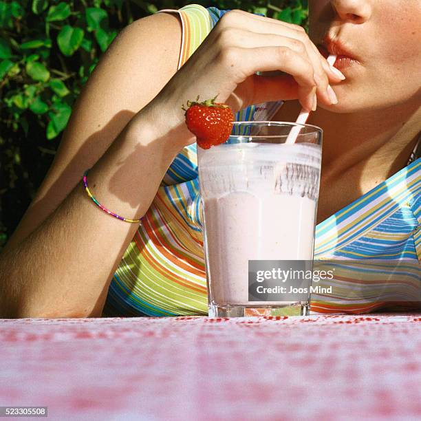 young woman drinking strawberry milk shake - champs et lait photos et images de collection