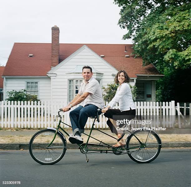 man and woman riding tandem bicycle - tandem bicycle foto e immagini stock