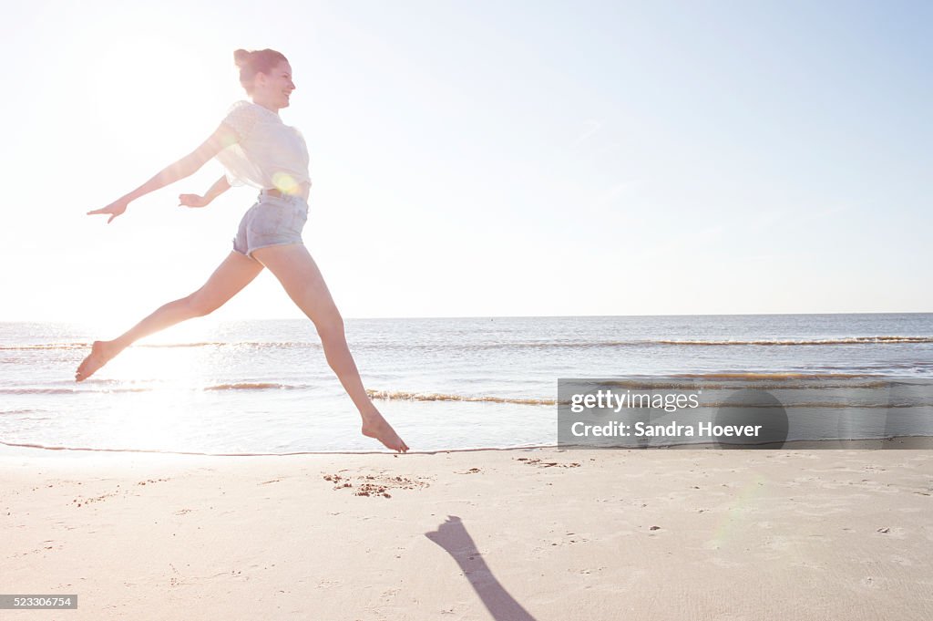 Woman jumping in sunset on beach