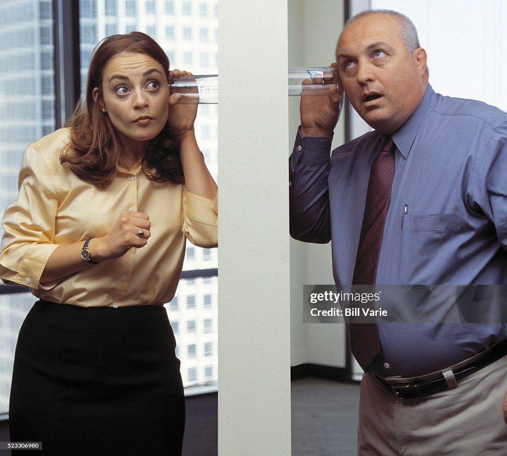 Workers Listening with Glasses Against Wall