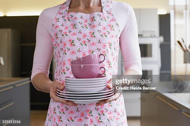 woman carrying stack of dishes - apron stock pictures, royalty-free photos & images