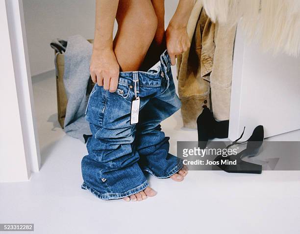 woman trying on jeans - vestir se fotografías e imágenes de stock