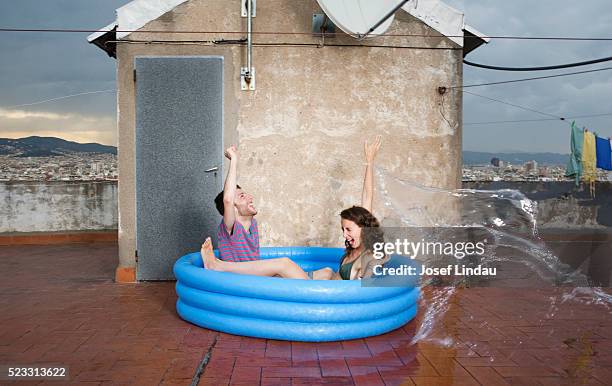 couple being splashed with water - rooftop pool imagens e fotografias de stock