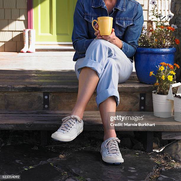 woman sitting on steps - cafe con piernas fotografías e imágenes de stock