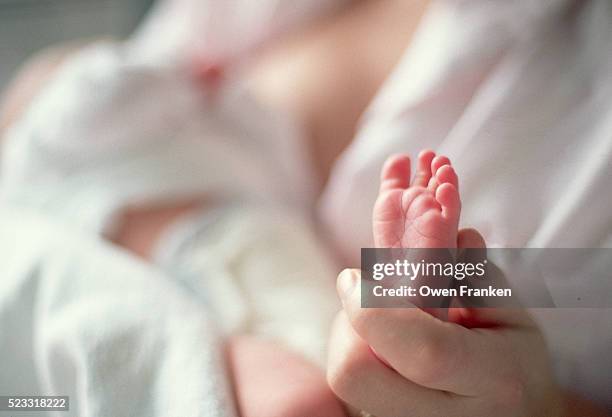 mother holding newborn's tiny foot - pies fotografías e imágenes de stock