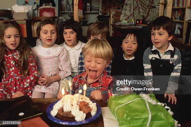 boy blows out candles for his fourth birthday - happy birthday vintage fotografías e imágenes de stock