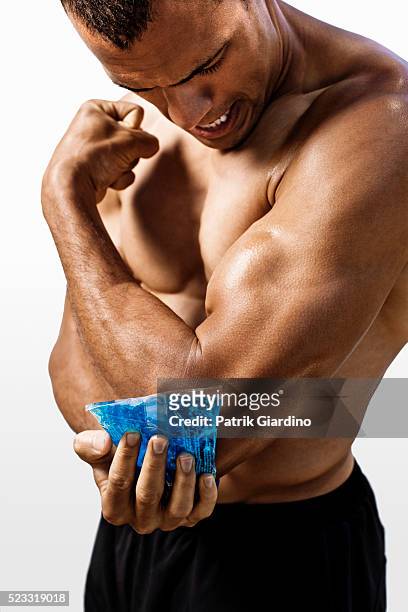 man applying cold pack to sore elbow - cold sore stock pictures, royalty-free photos & images