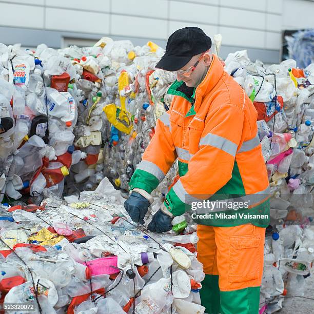 worker at recycling center tying bundle - centro de reciclaje fotografías e imágenes de stock