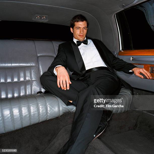 man wearing dinner jacket in the back seat of limousine - millionnaire stock pictures, royalty-free photos & images