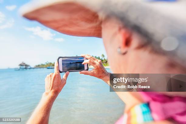 a woman on vacation in belize, photographing the ocean with a smartphone. - robb reece stock pictures, royalty-free photos & images