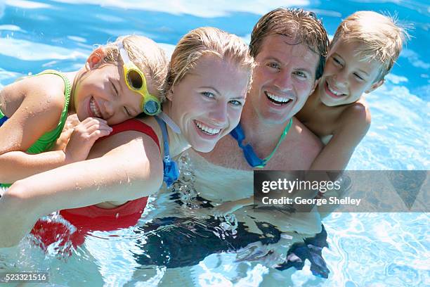 family hugging in swimming pool - public swimming pool stock pictures, royalty-free photos & images