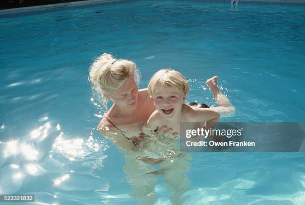 mother holding her son in a swimming pool - 1990s woman stock pictures, royalty-free photos & images