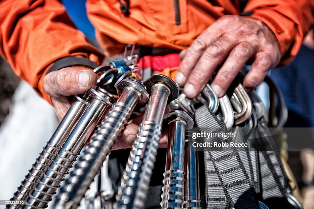 Male ice climber holding ice screws