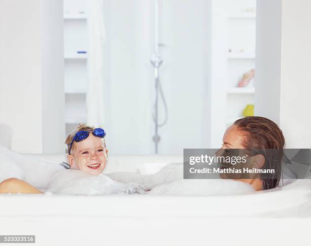 mother and baby son in bubble bath - kid bath mother stock-fotos und bilder