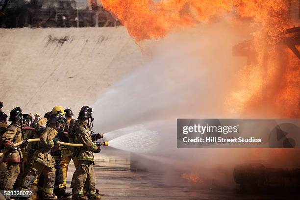 firefighters extinguishing a blaze - extinguir fotografías e imágenes de stock