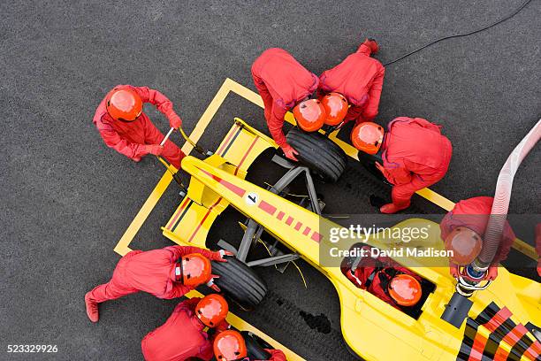 pit crew fueling and changing tires on racecar - pit imagens e fotografias de stock