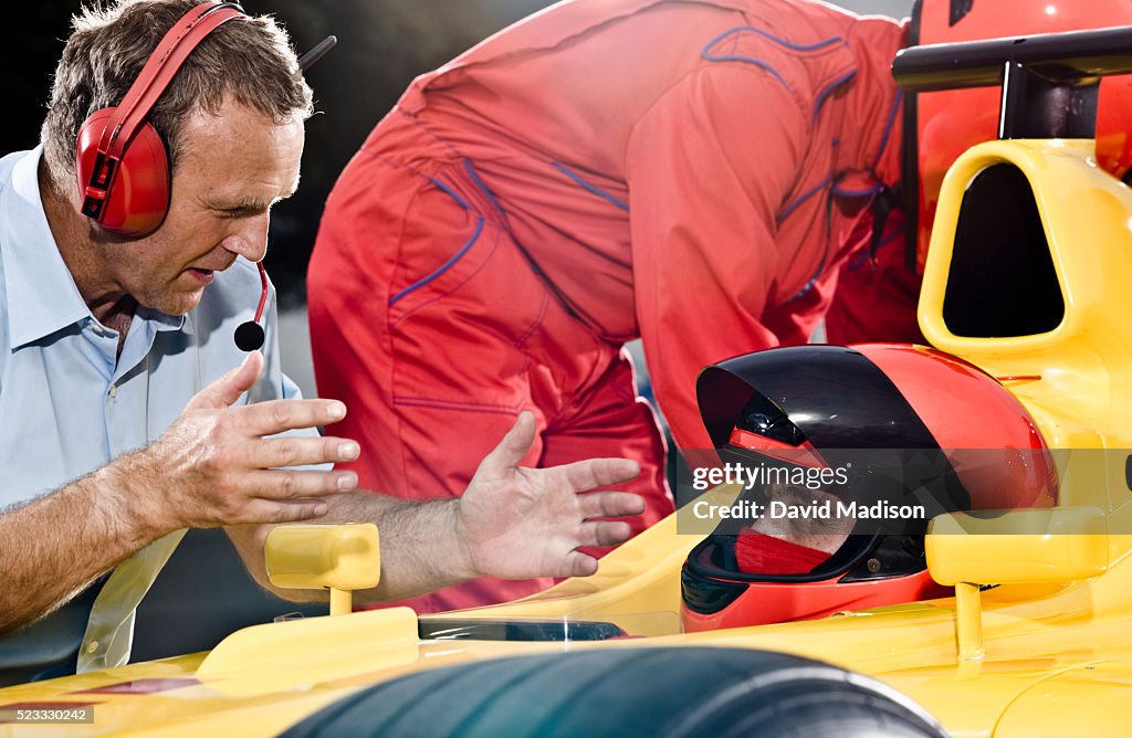 Race Team Leader Discussing Strategy With Racecar Driver