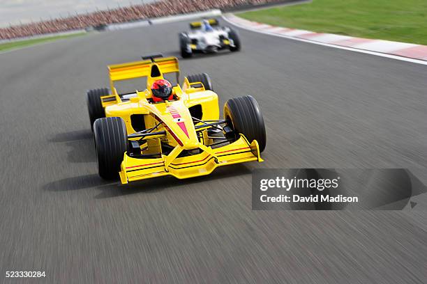 two open-wheel single-seater racing car racecars racing down racetrack - car racing stadium stock pictures, royalty-free photos & images