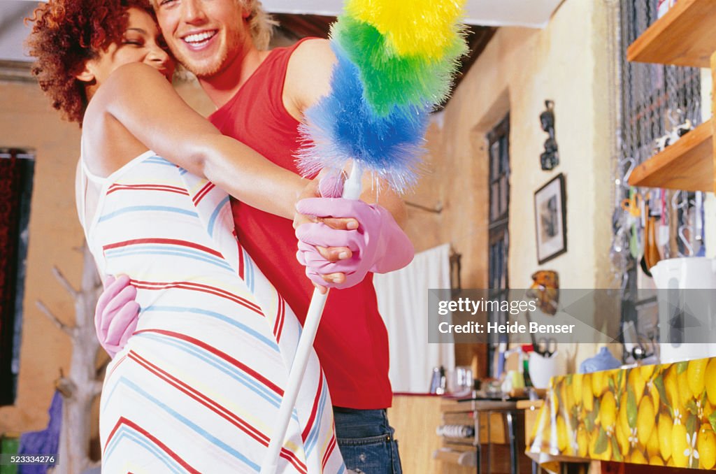 Young couple dancing, man holding feather duster