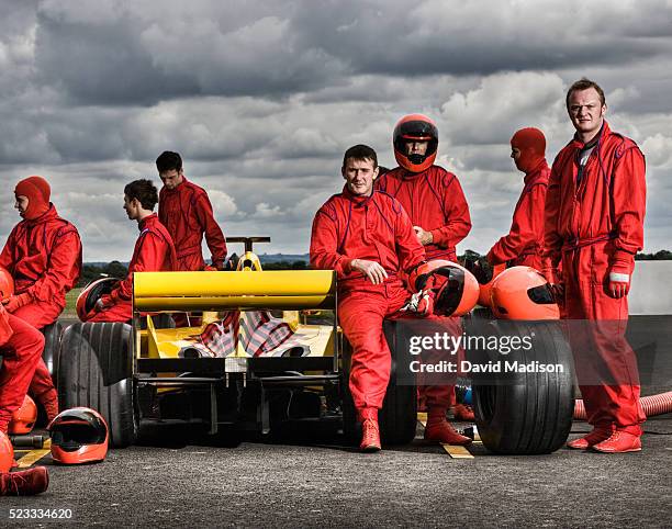 racing team resting around racecar under stormy sky - pit stock-fotos und bilder