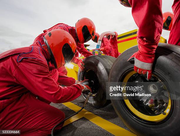 three man team changing tire on formula one racecar - car racing stock-fotos und bilder